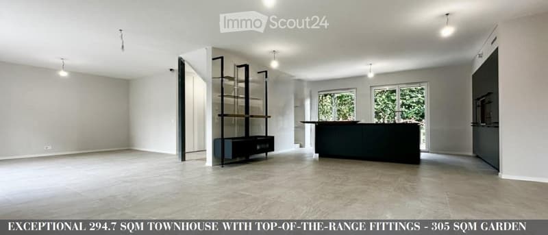 Open-plan space with a modern kitchen island, sleek shelving unit, and large windows letting in natural light.