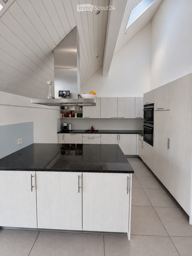 Modern kitchen with white cabinets, black countertop, built-in oven, and various small appliances and decorative items on the counter.