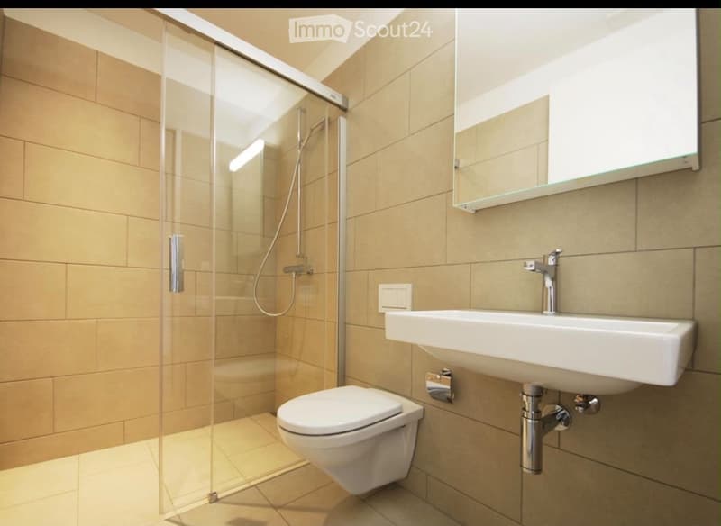 Modern bathroom with beige tiles, a glass-enclosed shower, a toilet, a sink with a mirror above it, and a modern faucet.