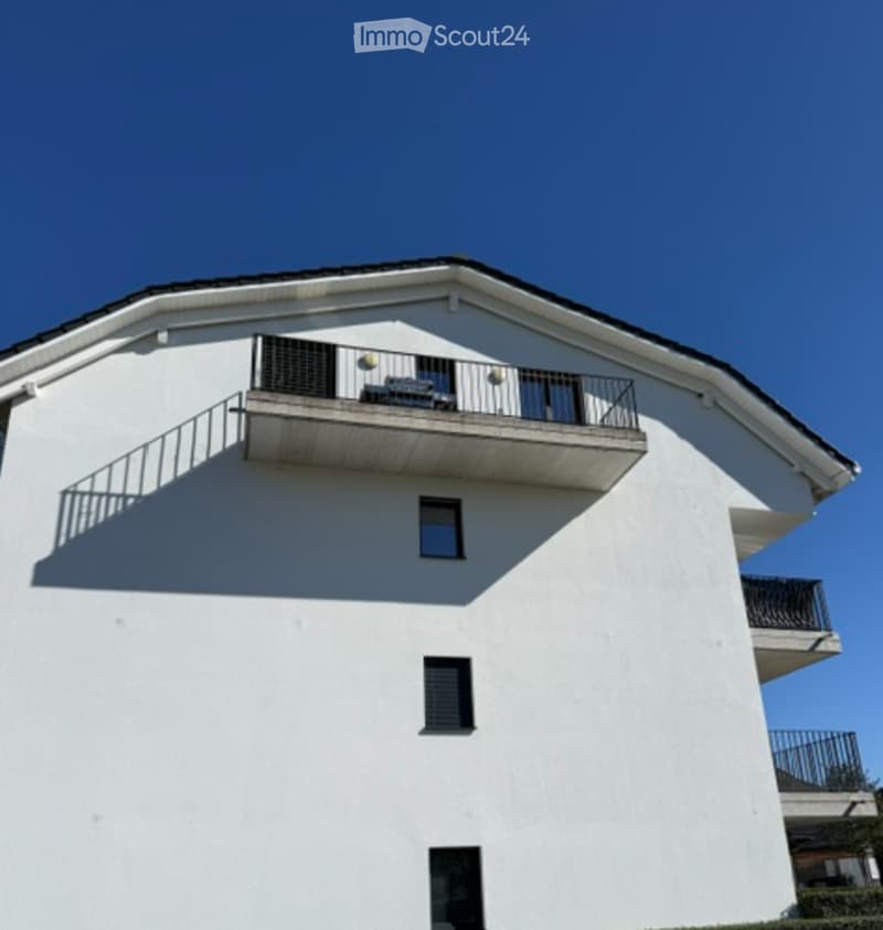 Modern two-story white building with multiple balconies and large windows.
