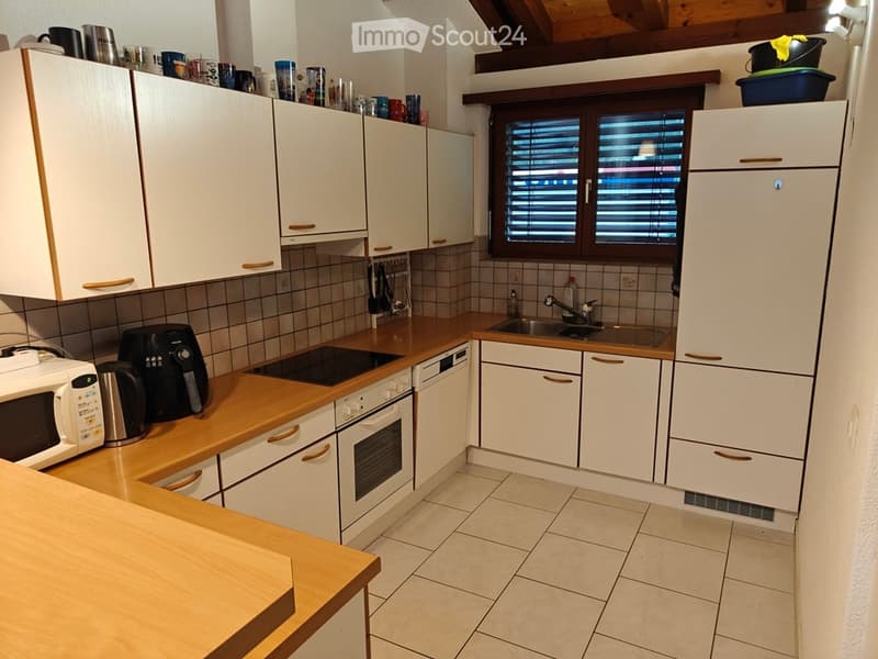 Modern kitchen with white cabinets, wooden countertops, and various appliances including a microwave, oven, fridge, and air fryer.
