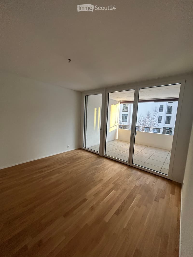 Empty room with wooden flooring and large sliding glass doors leading to a balcony.