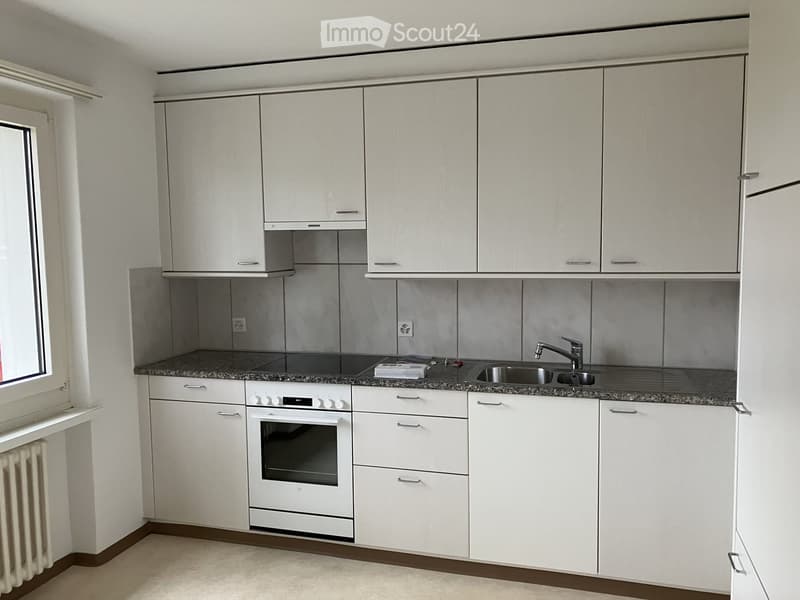 Modern kitchen with white cabinets, granite countertop, stainless steel sink, and built-in oven.
