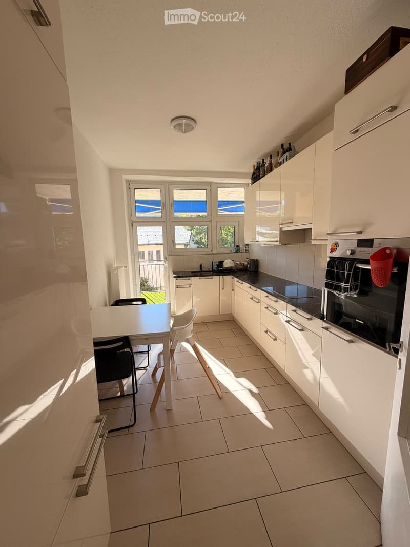 Modern kitchen with white cabinets, black countertops, and a dining area with a table and chairs.