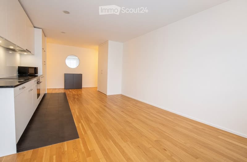 Empty room with light-colored walls, wooden flooring, and white cabinetry. No furniture or appliances are present.