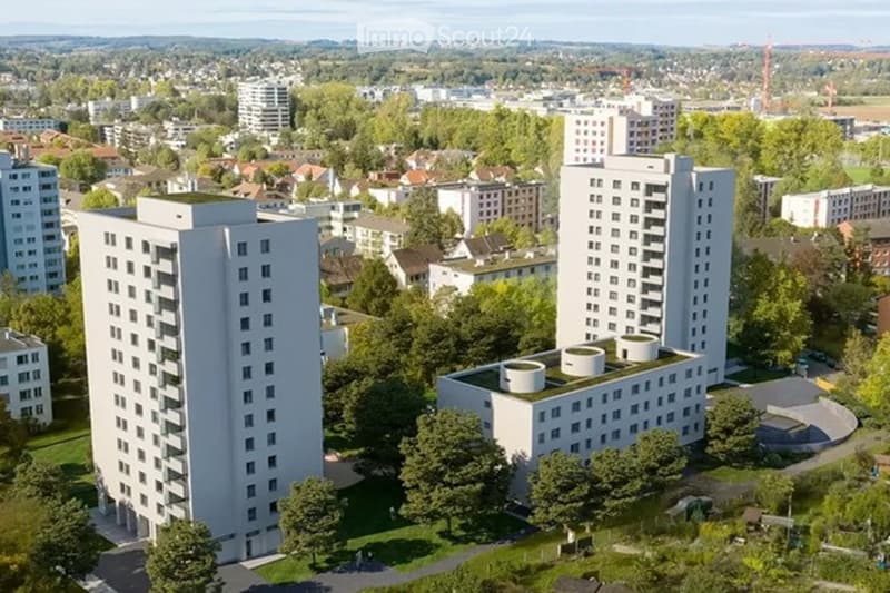 Aerial view of a modern residential complex with multiple high-rise buildings, surrounded by greenery and other structures in an urban setting.