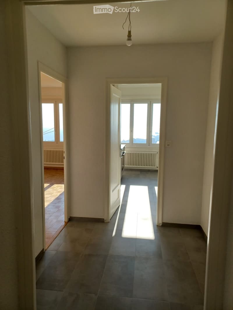 Empty hallway with tiled floor, white walls, and two open doors leading to other rooms.