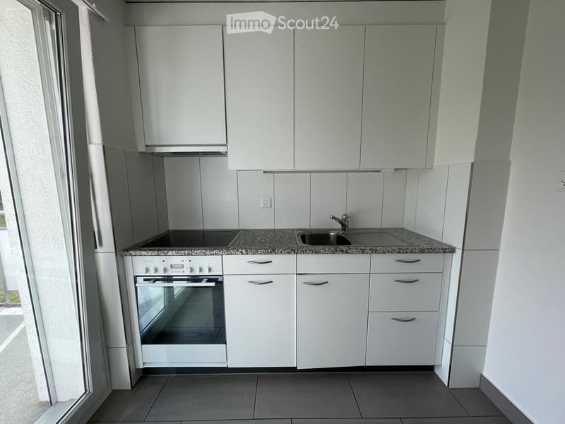 Modern kitchen with white cabinets, granite countertop, built-in oven, and stainless steel sink.
