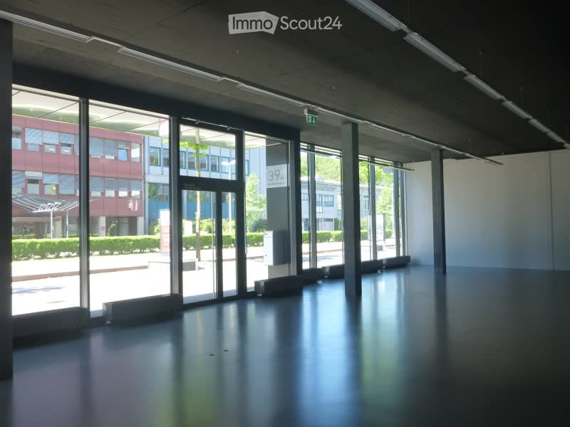 Empty, modern interior space with large glass windows and polished dark flooring. Minimalist design with no furniture or equipment visible.