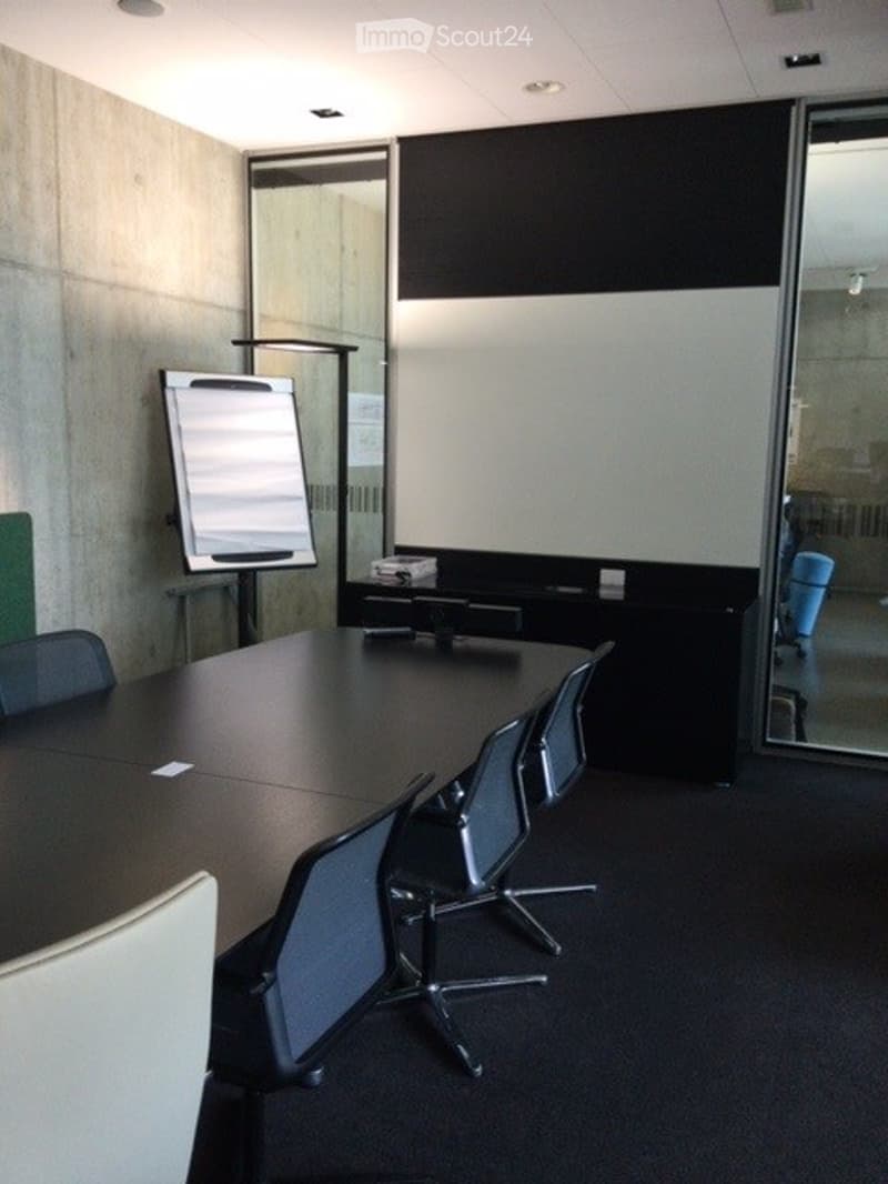 Conference room with a large table, several chairs, a screen, and a whiteboard.