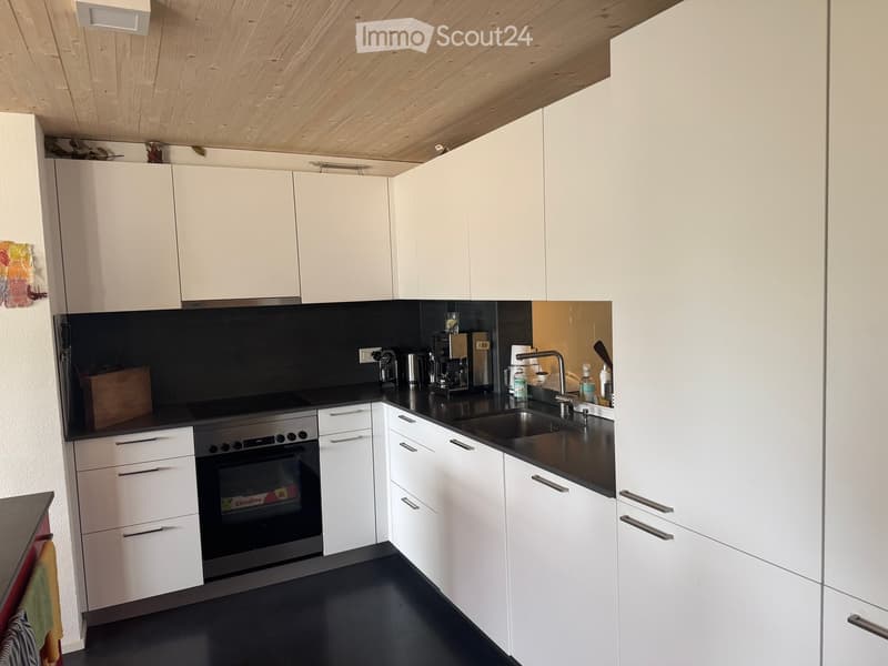 Modern kitchen with white cabinets, black countertops, and stainless steel appliances including an oven and sink.