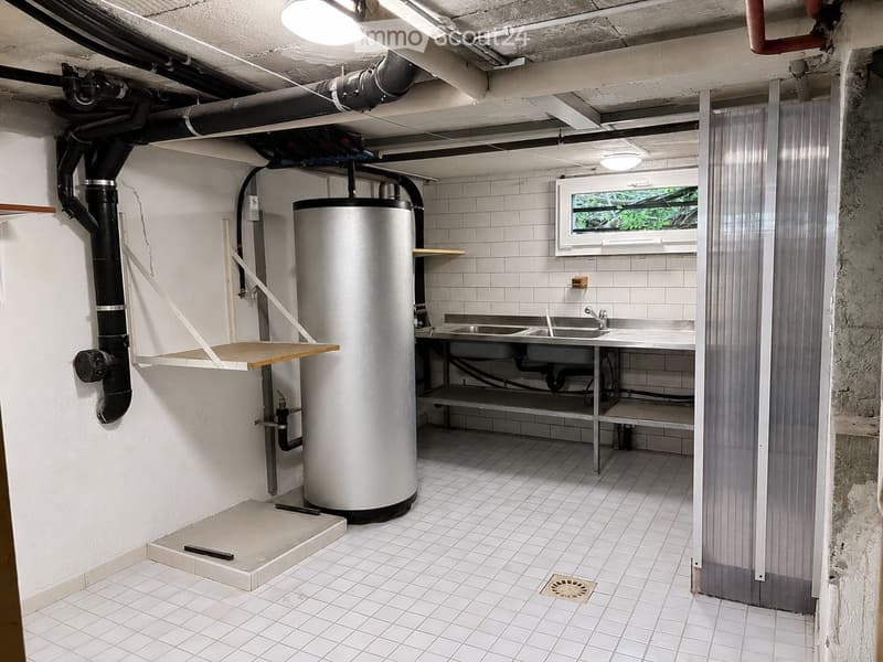 Utility bathroom with white tiled walls and floor, a water heater, a sink with a faucet, and a small shelf.