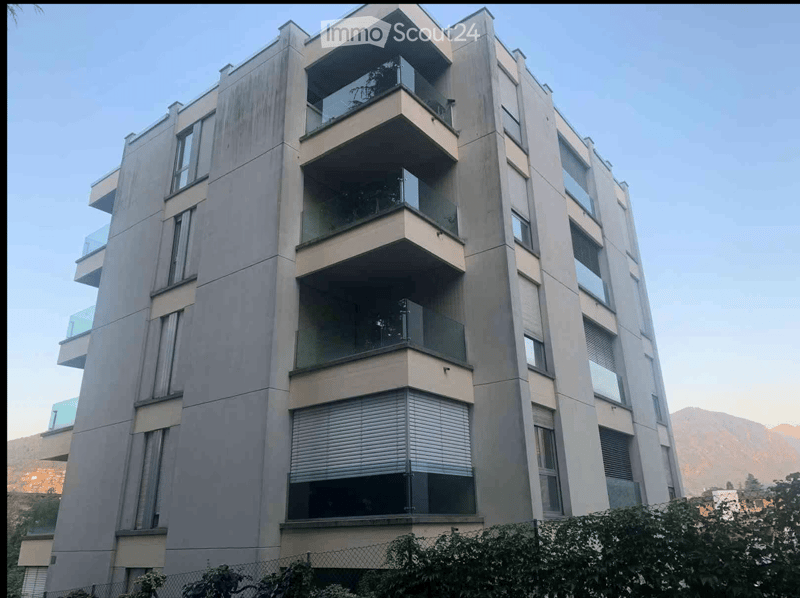 Modern multi-story residential building with balconies and large windows, featuring a sleek, contemporary design.