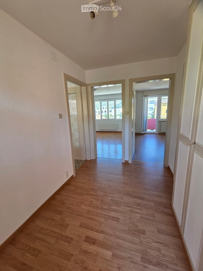Empty hallway with wooden flooring, white walls, and multiple doors leading to other rooms.