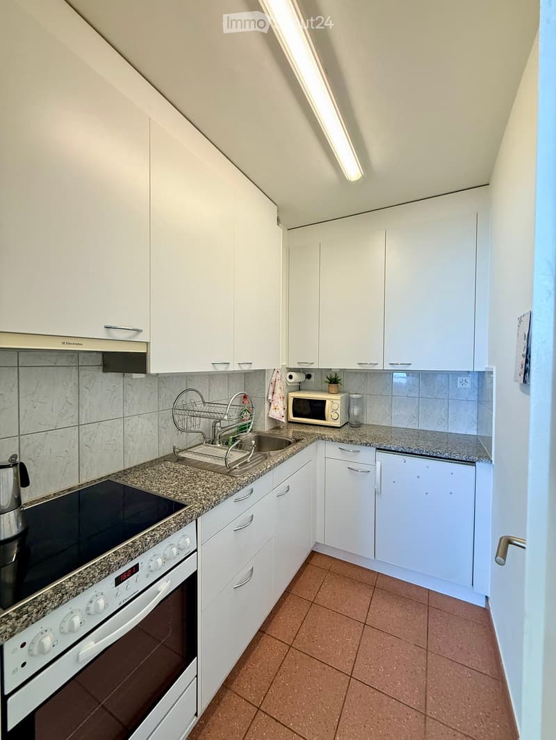 Modern kitchen with white cabinets, granite countertops, stainless steel appliances, and a tiled backsplash.