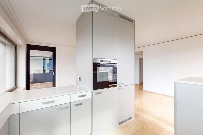 Modern kitchen with white cabinets, a built-in oven, and a light wooden floor.
