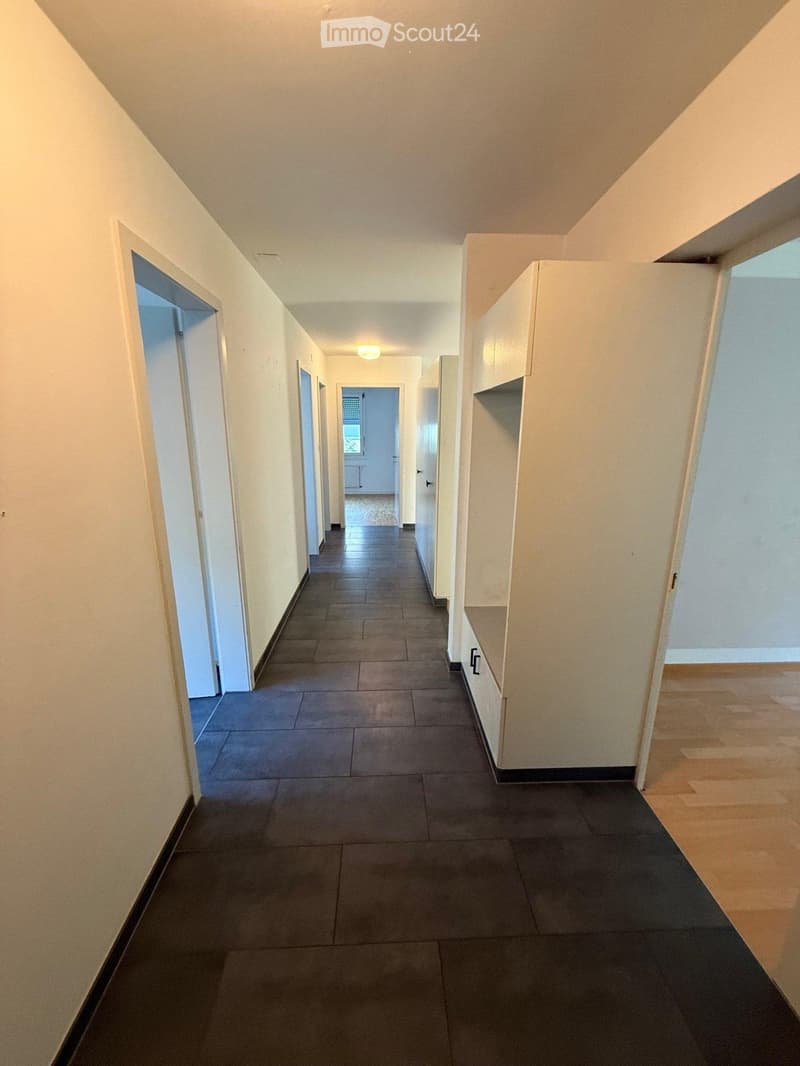Empty hallway with tiled floor, white walls, and several doors leading to adjacent rooms.