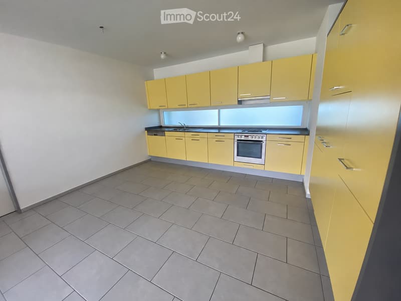 Modern kitchen with yellow cabinets, tiled floor, stainless steel oven, sink, and faucet.