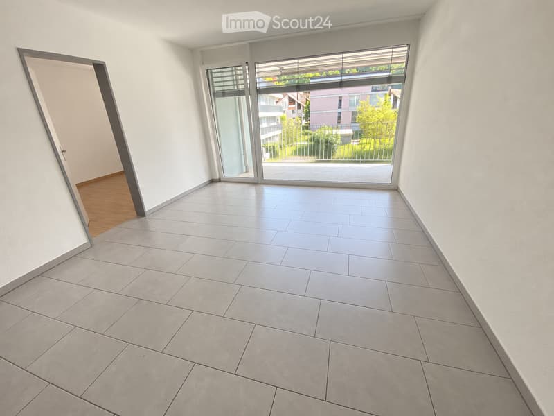 Empty room with grey tiled floor, white walls, and large sliding glass doors leading to a balcony area.