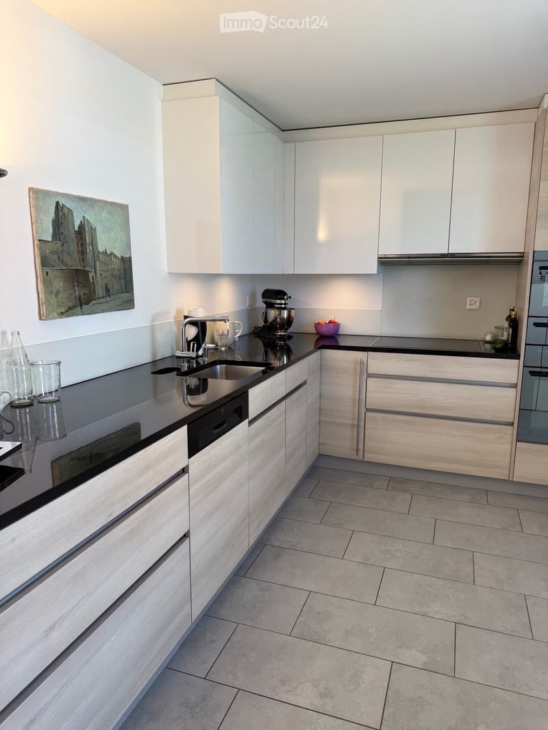 Modern kitchen with white cabinets, stainless steel sink, dishwasher, mixer, and various kitchen items on the counter.