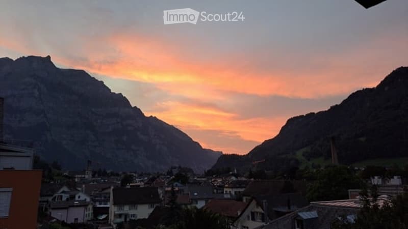 Panoramic view of a town nestled in a valley surrounded by mountains at sunset.
