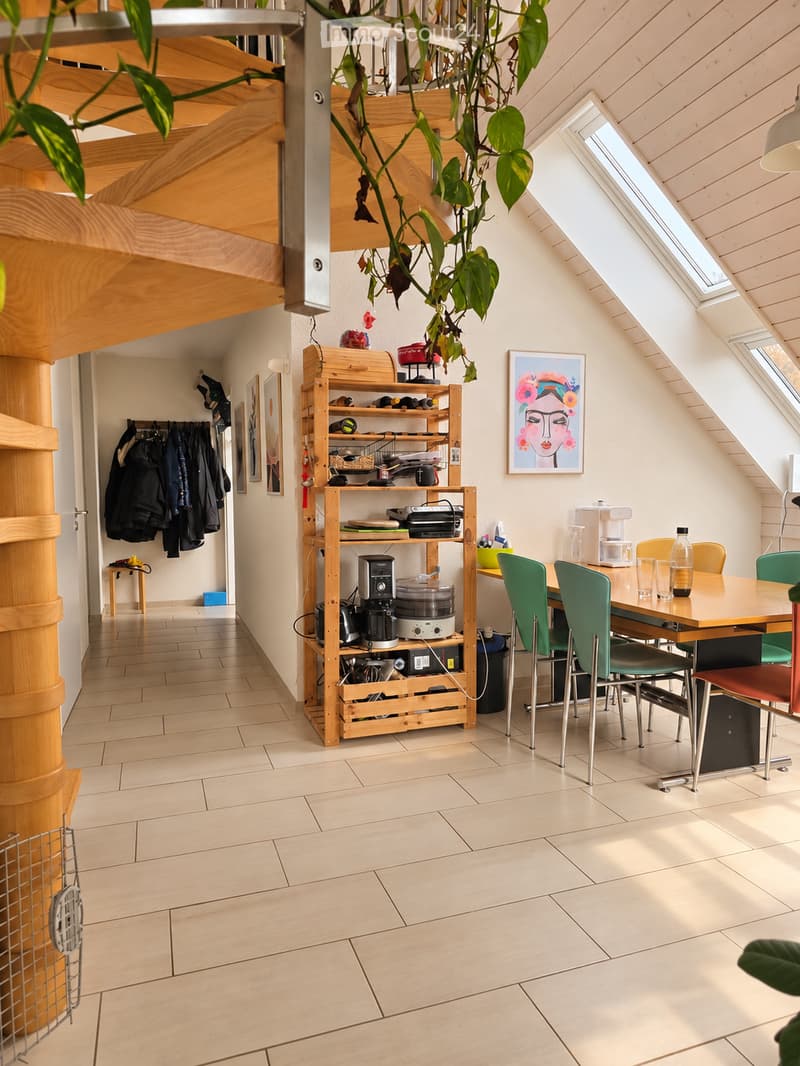 Bright, open kitchen and dining area with wooden shelves, a dining table with chairs, and a coffee maker on the counter.