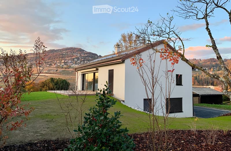 Modern single-story house with white exterior, large windows, and a panoramic view of a valley and hills in the background.