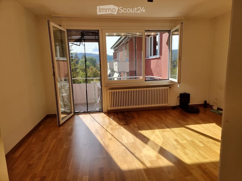 Empty room with wooden flooring, large windows, and a radiator. The room is unfurnished and has natural light streaming in.