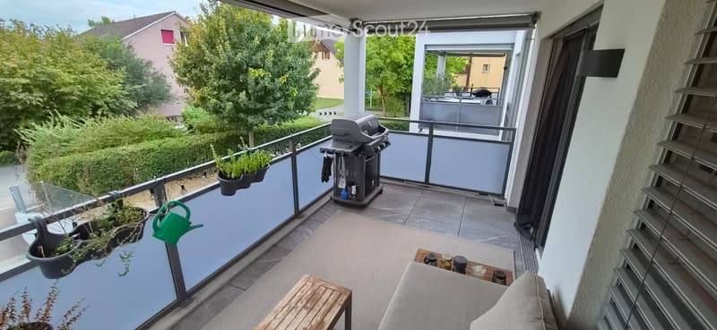 Balcony with a small seating area, a table, a grill, and potted plants.