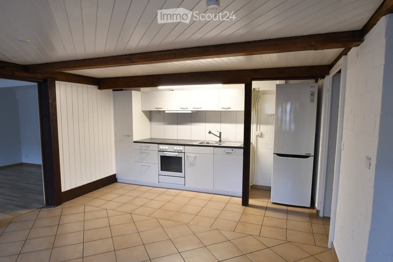 Modern kitchen with white cabinets, stainless steel appliances, tiled floor, and exposed wooden beams on the ceiling.