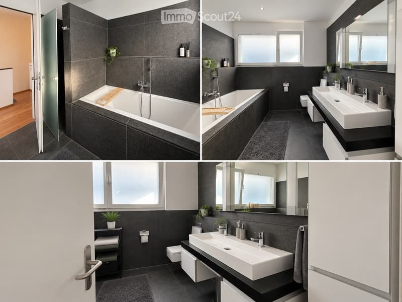 Modern bathroom with dark grey tiles, a large bathtub, double sink, mirror, and a toilet. Features include a glass shower enclosure, wooden bath tray, and small potted plants on shelves.
