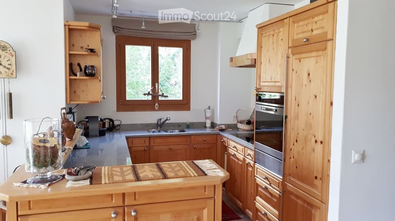 Bright kitchen with wooden cabinets, granite countertops, and stainless steel appliances. Features a window, sink, and decorative items on the counter.