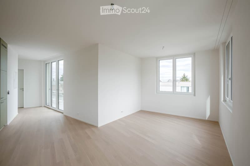 Empty room with light wooden flooring, white walls, and large windows allowing natural light. The space is unfurnished, with no visible furniture or equipment.