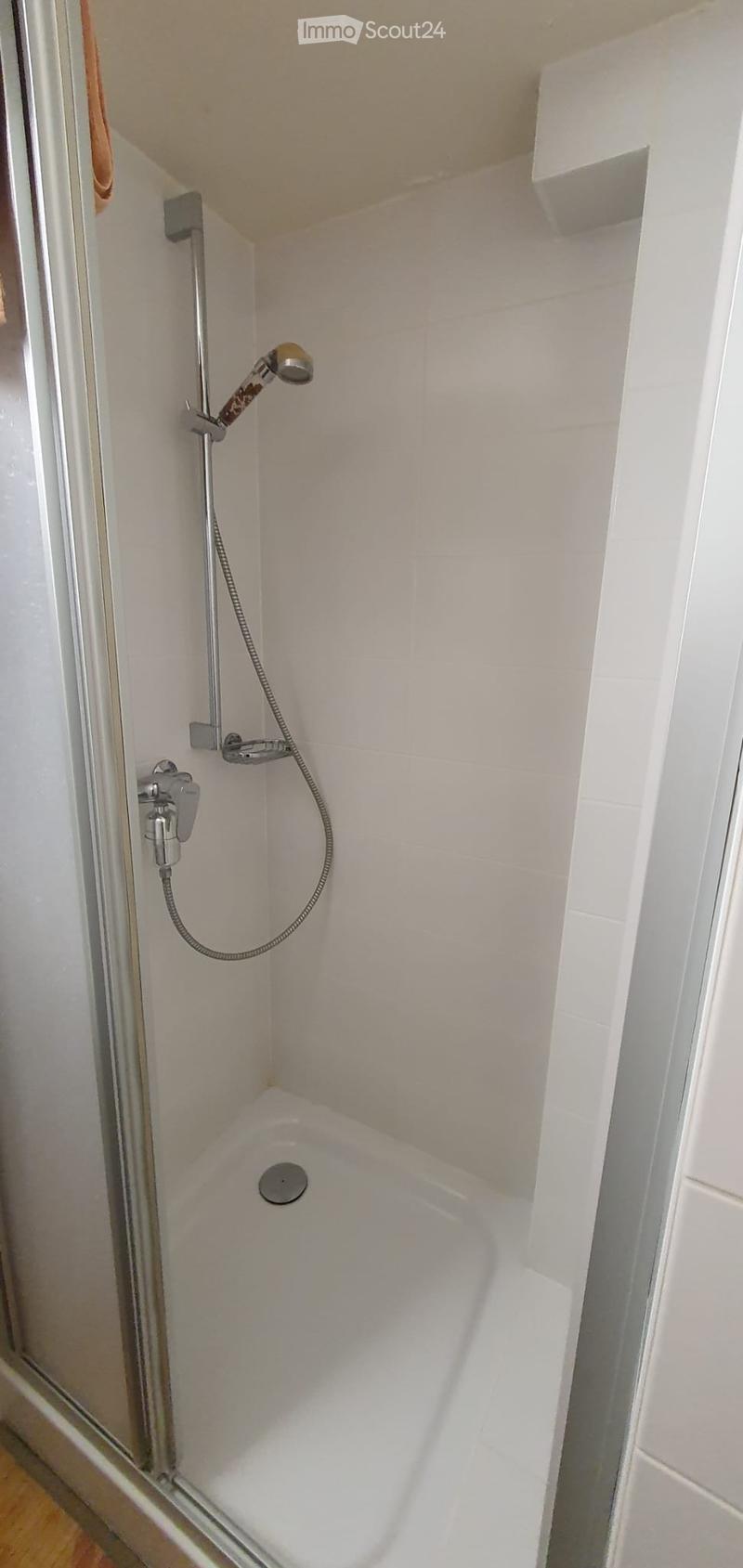 Modern bathroom with a white bathtub and a handheld showerhead attached to the wall.