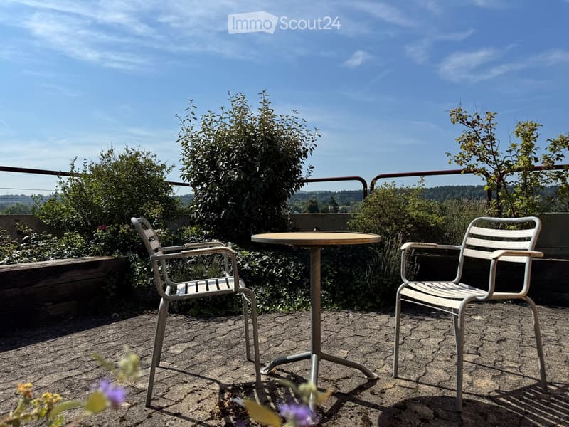 Balcony / Terrace. Balcony with a round table and two chairs, surrounded by greenery and a clear blue sky.
