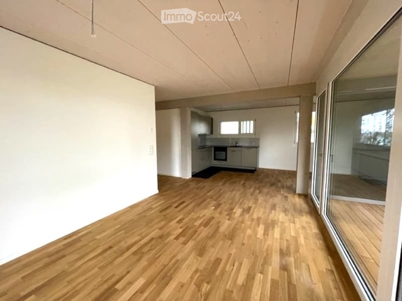 Empty room with wooden flooring, white walls, and large windows. No furniture or equipment present.