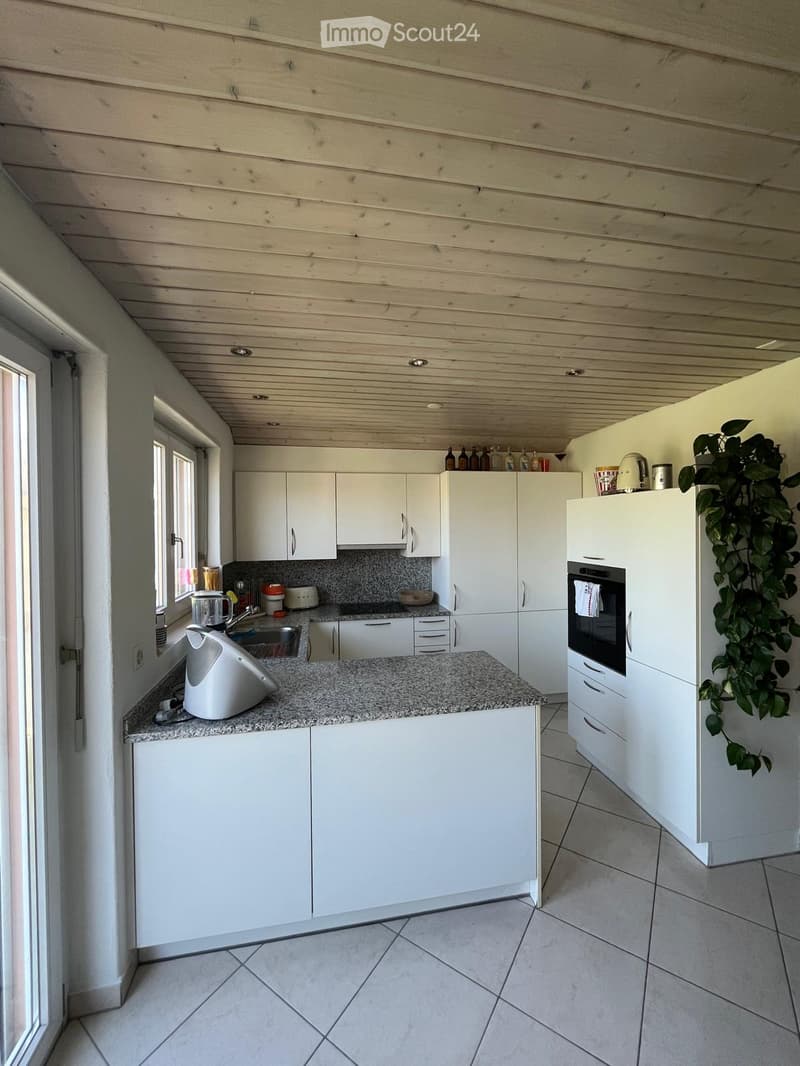 Modern kitchen with white cabinets, granite countertop, and built-in oven. Features a window, sink, and various appliances.