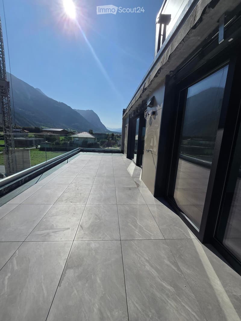 Modern balcony with large glass windows, tiled floor, and scenic mountain view.