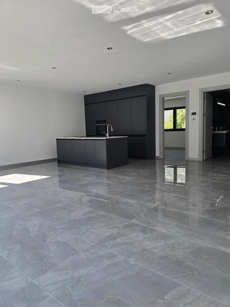 Modern kitchen with dark grey cabinets, a central island, and a polished marble floor. The space is well-lit with recessed lighting and features a sleek, minimalist design.