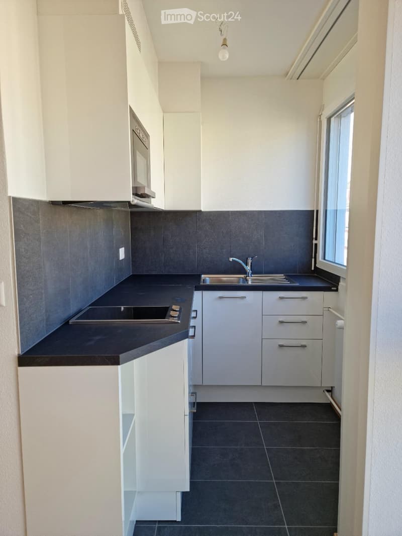Modern kitchen with white cabinets, dark countertops, and a stainless steel sink.