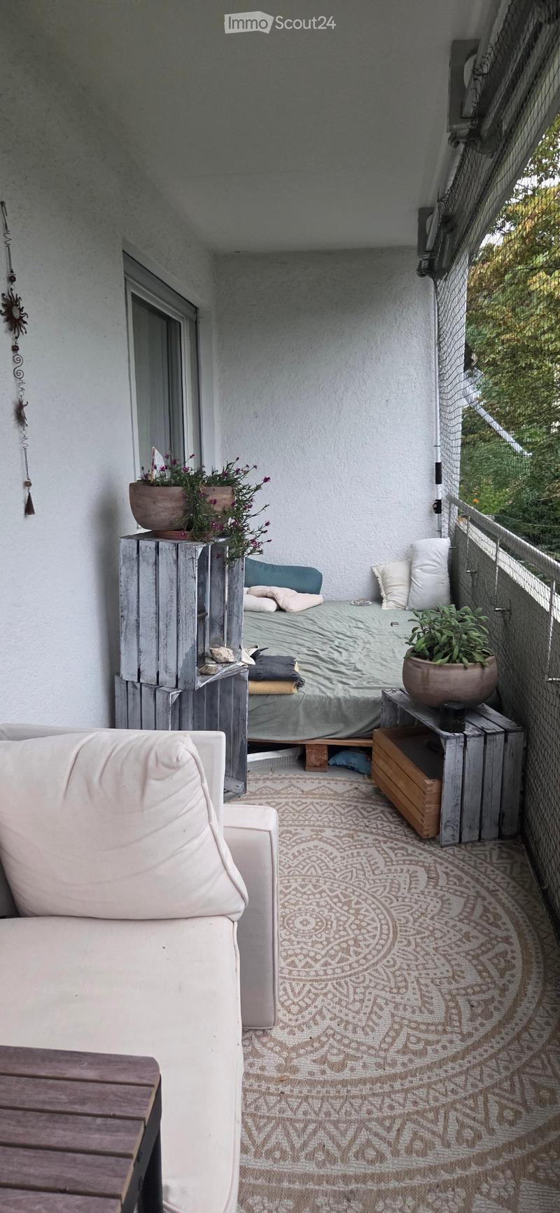 Balcony with a sofa, a small bed, a table, and potted plants.
