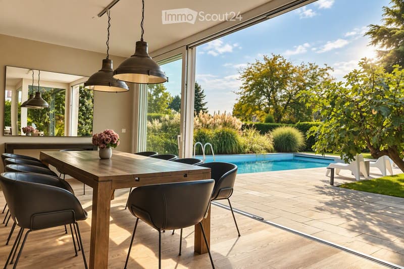Bright dining area with a wooden table, black chairs, and a vase of flowers, large windows overlooking a swimming pool and garden.