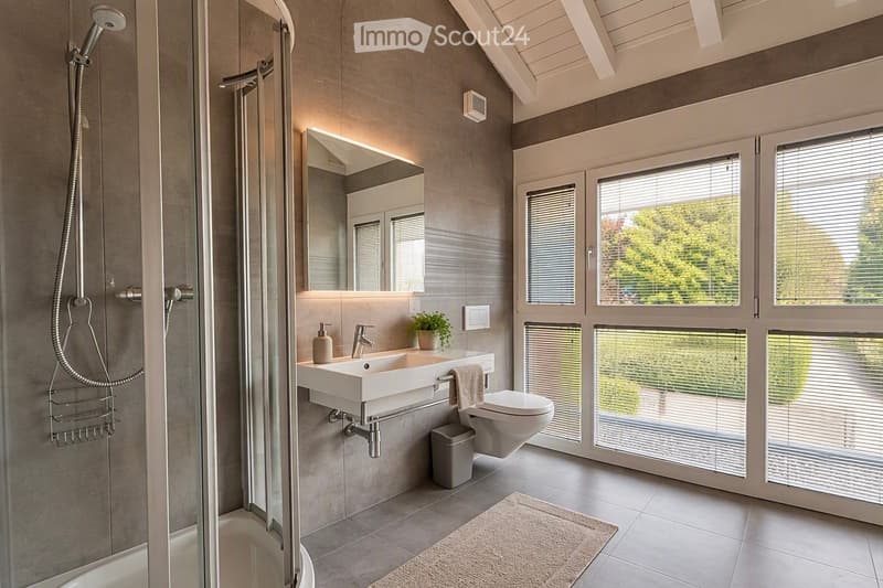 Modern bathroom with a large window, a walk-in shower, a sink with a mirror, a toilet, and a small plant on the sink counter.