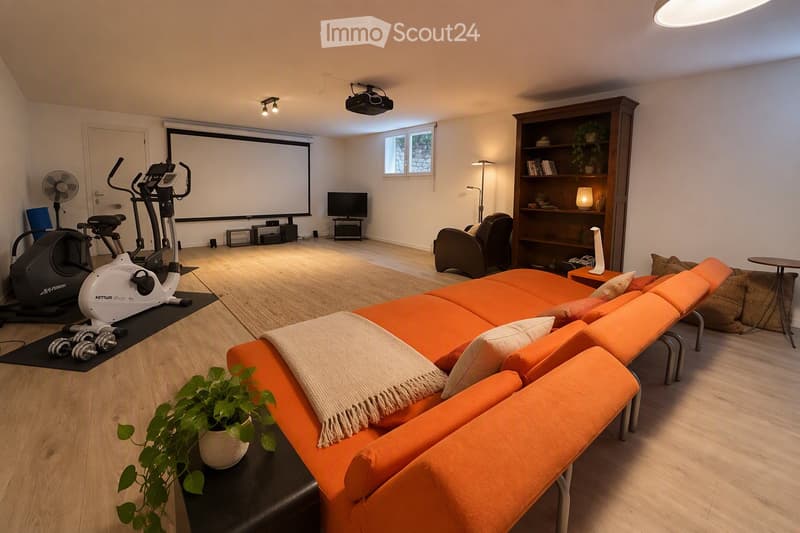 Modern living room with orange sectional sofa, coffee table, exercise bike, dumbbells, bookshelf, and projector screen.