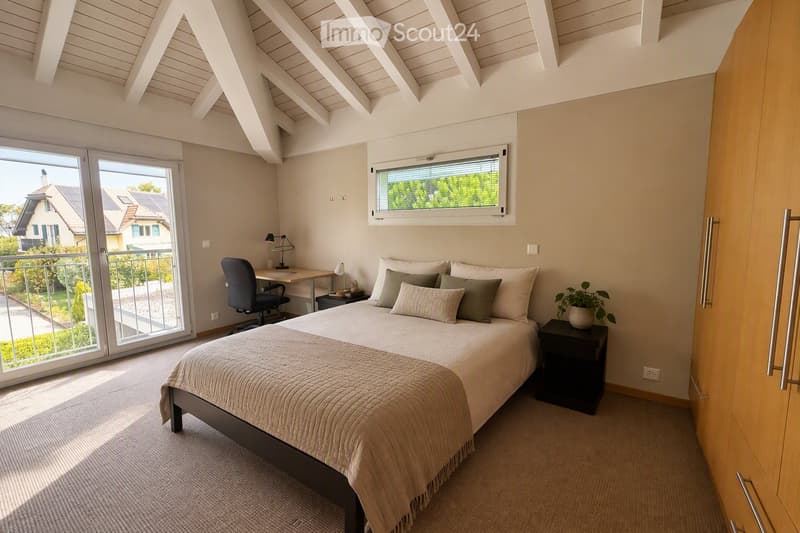 Bright bedroom with a large bed, nightstand, desk, chair, and a view of the balcony.