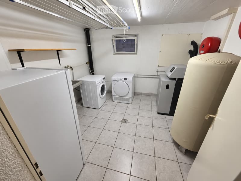 Laundry room with tiled floor, white washing machine, dryer, water heater, and a shelf.
