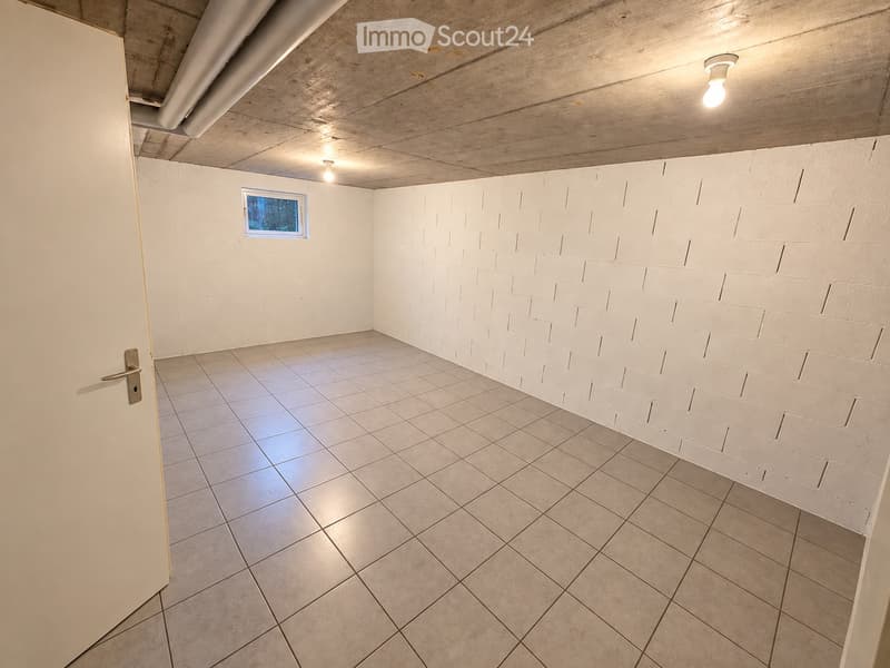 Empty room with white brick walls, tiled floor, and a small window. Exposed wooden ceiling with recessed lighting.