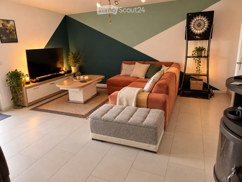 Modern living room with a sectional orange sofa, ottoman, coffee table, TV stand, floor lamp, side table, potted plants, and a dartboard on a shelf.