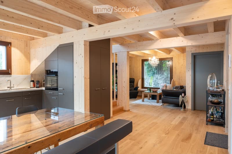 Open-plan living and dining area with exposed wooden beams, modern kitchen, and comfortable seating.