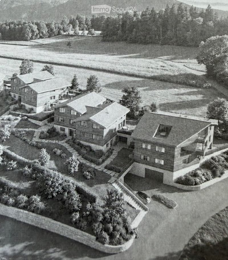 Aerial view of a residential complex with multiple houses, a garage, and landscaped gardens.